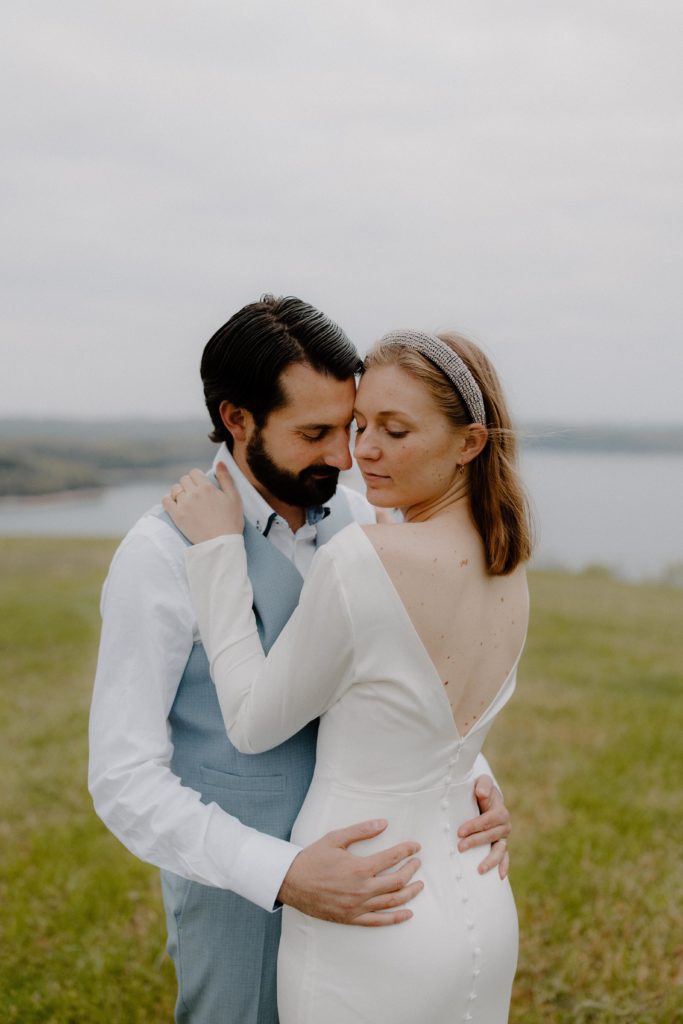 bride and groom cuddling close with lake in background-- best places to elope in arkansas