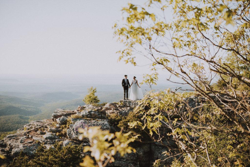 bride and groom holding hands on cliff-- best arkansas elopement locations