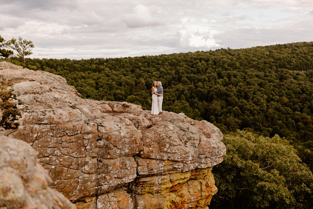 a couple holding each other on a rock ledge -- arkansas elopement photographer
