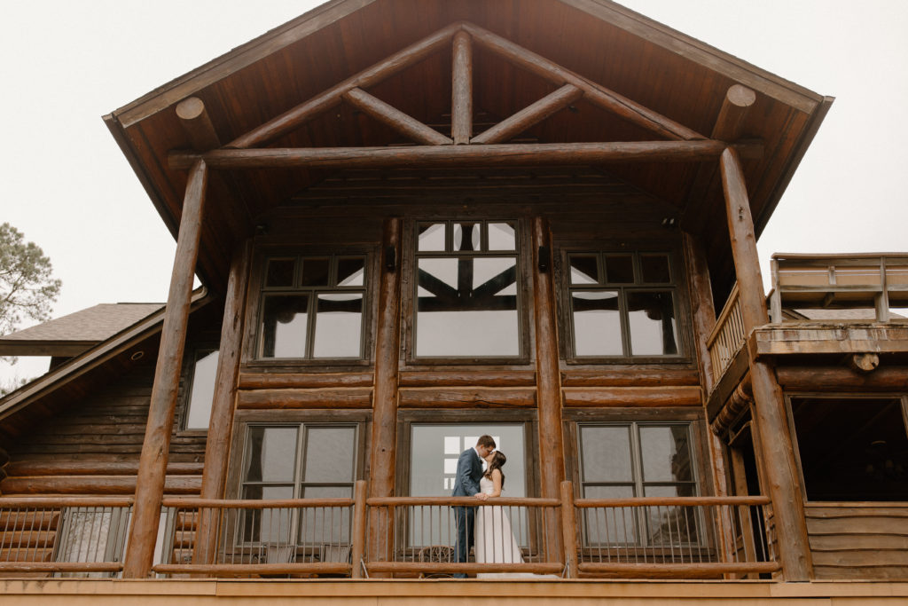 couple kissing on balcony of log cabin -- arkansas wedding photographer