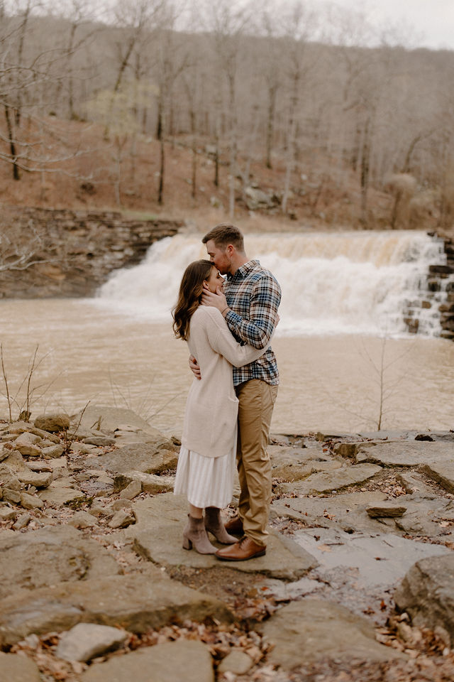 couple hugging with waterfall in background -- devils den engagement photos 