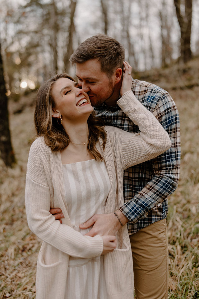 man kissing woman from behind while woman laughs -- northwest arkansas wedding photographer