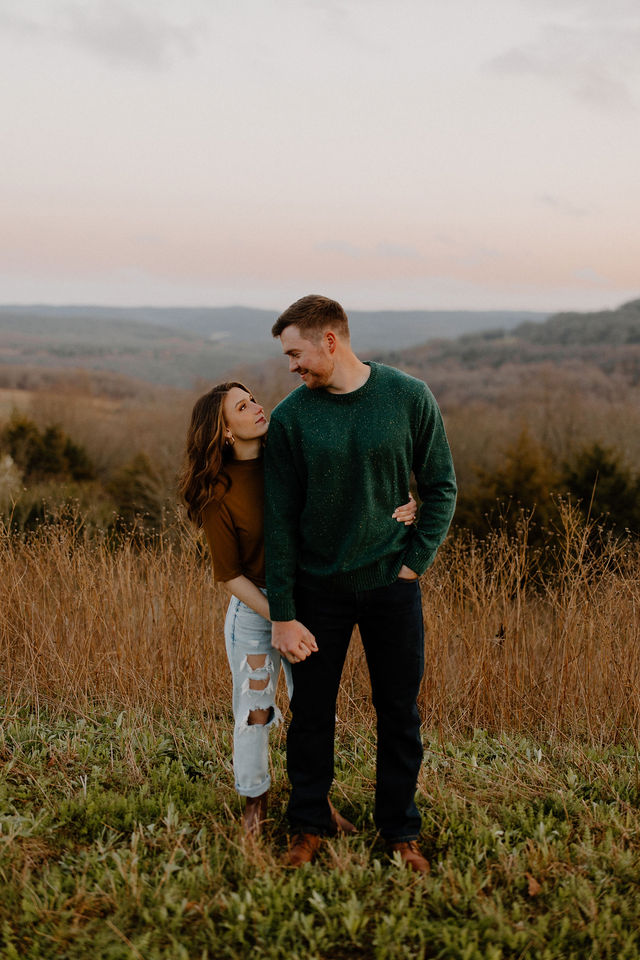 woman hugging man from behind in field-- arkansas engagement photographer