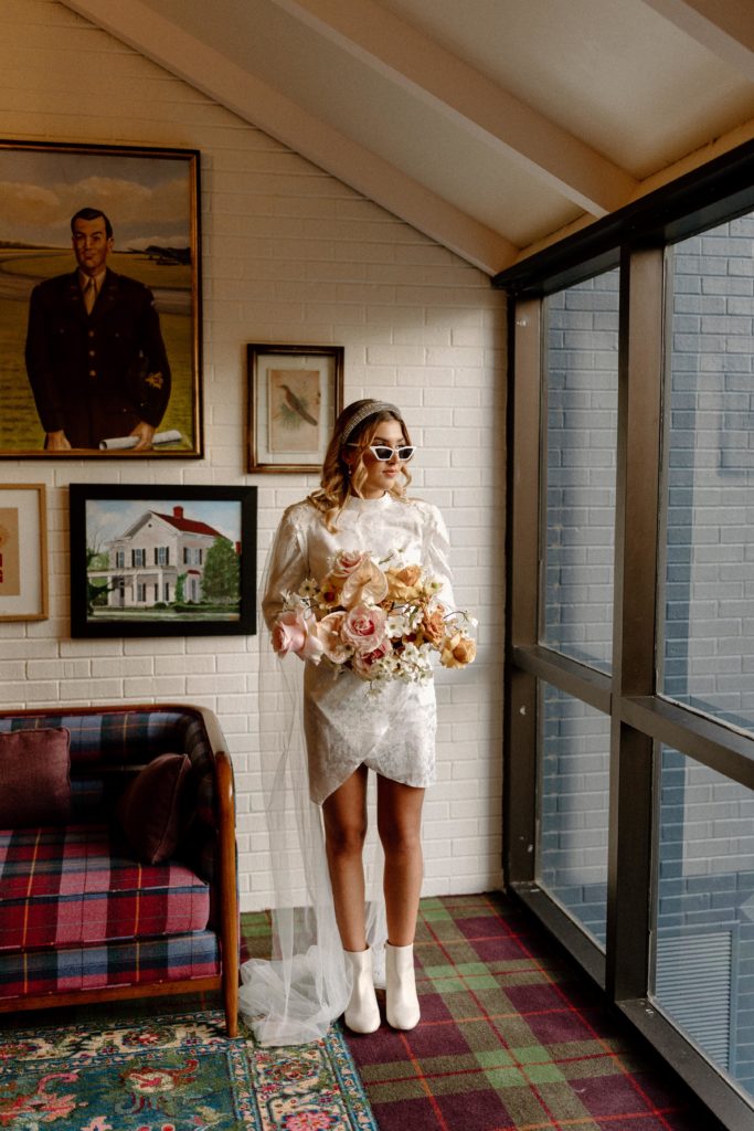 bride with sunglasses and bouquet looking outside window --arkansas elopement 