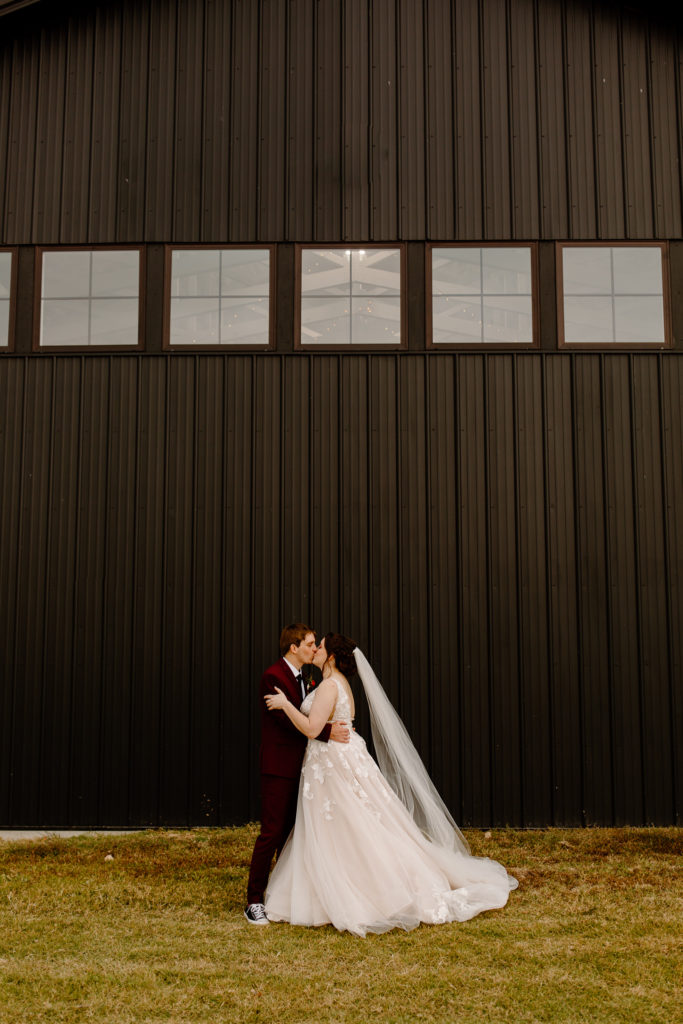 Bride and groom kissing with black wall behind them -- Willow Brooke Wedding venue 