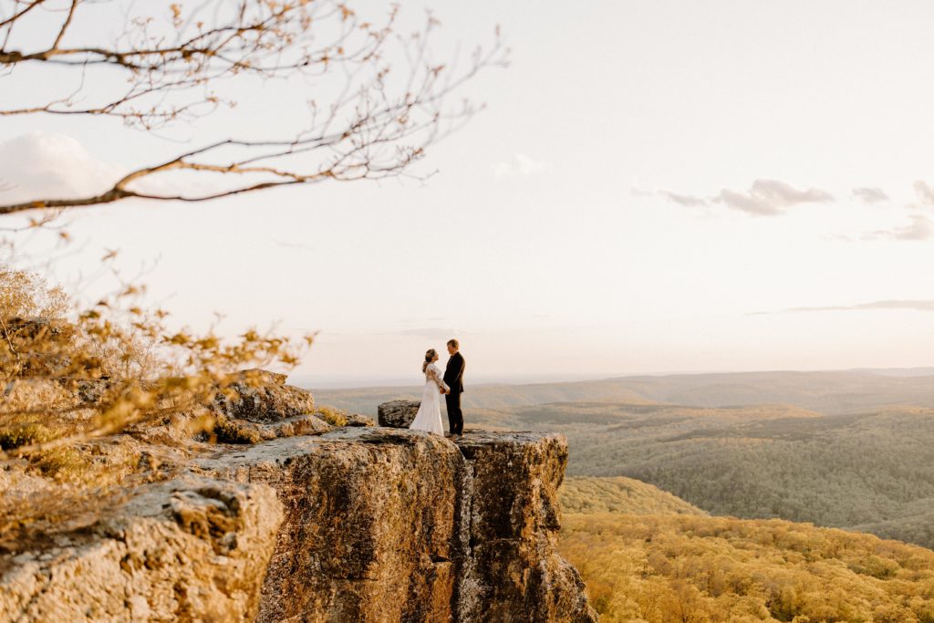 man and woman facing each other on scenic cliff arkansas elopement photography